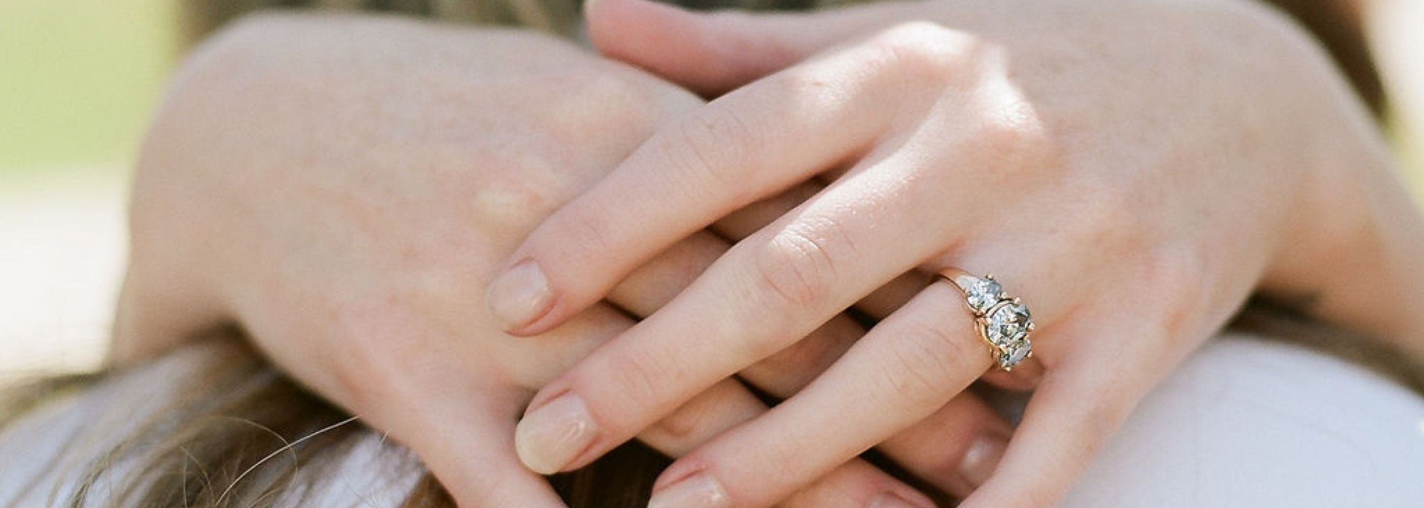 a woman's hands are wrapped in an embrace around a man's shoulders. She wears a lab grown diamond engagement ring