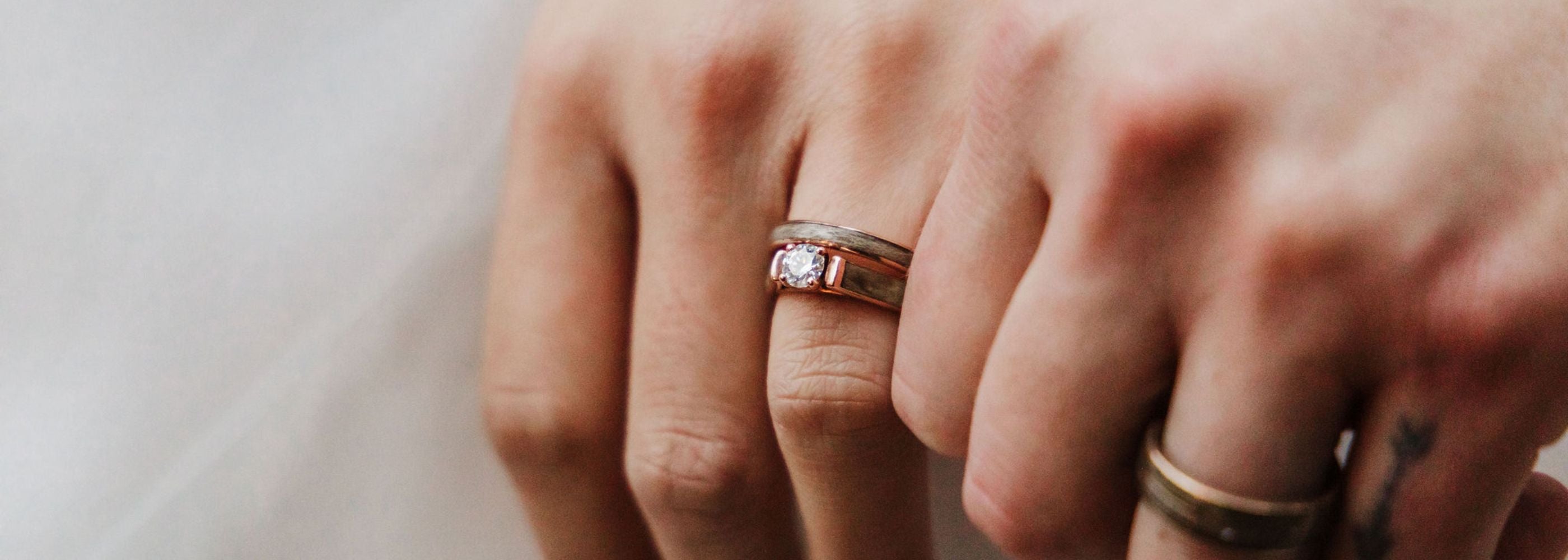 brides hold hands showing their wedding rings and wood engagement ring
