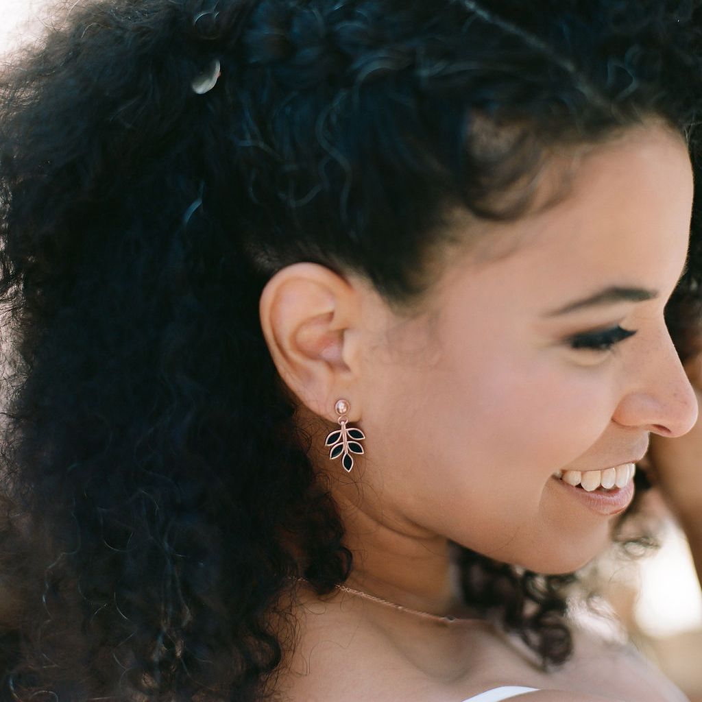 a woman smiling, wearing laurel leaf drop earrings with wood inlay
