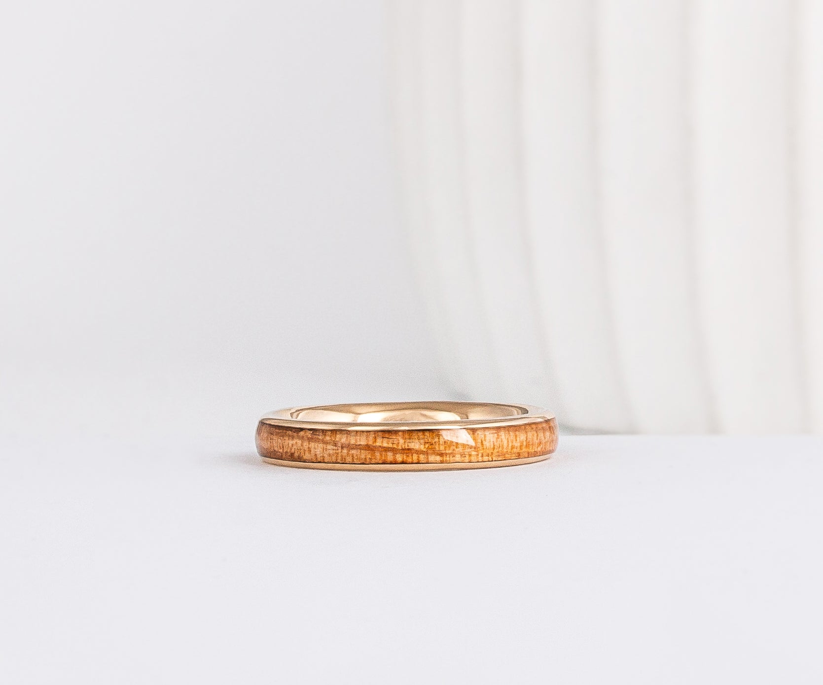 a slim, rounded yellow gold wedding band with a center inlay of american elm wood, giving it a tone on tone look
