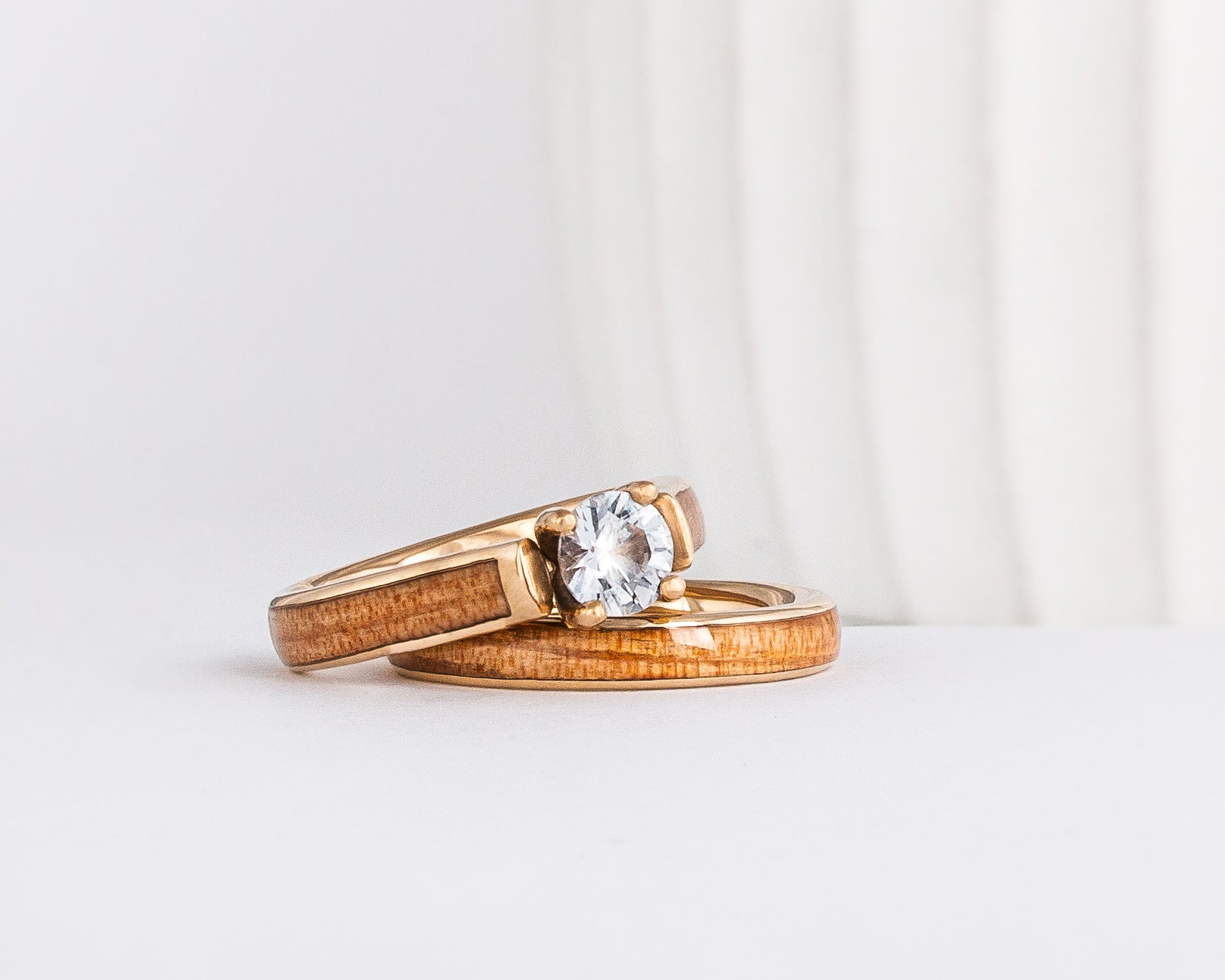 a wood wedding ring set made from yellow gold, american elm wood inlays, and a moissanite solitaire