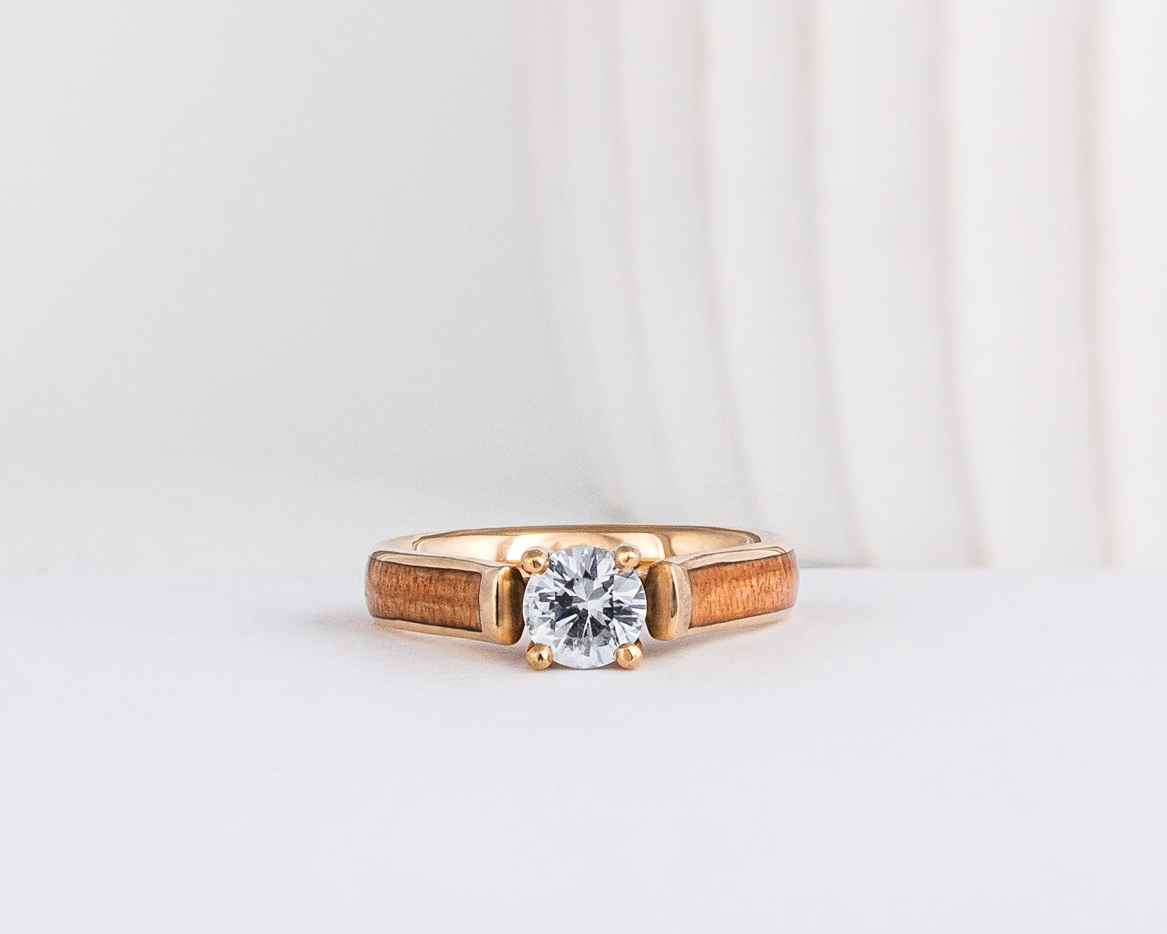 round cut lab grown diamond set beautifully in yellow gold and is shown with american elm wood inlays
