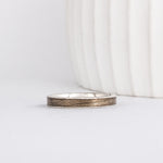 white gold band with a straight edge profile with thin gold borders outlining a neutral gray inlay of maple wood