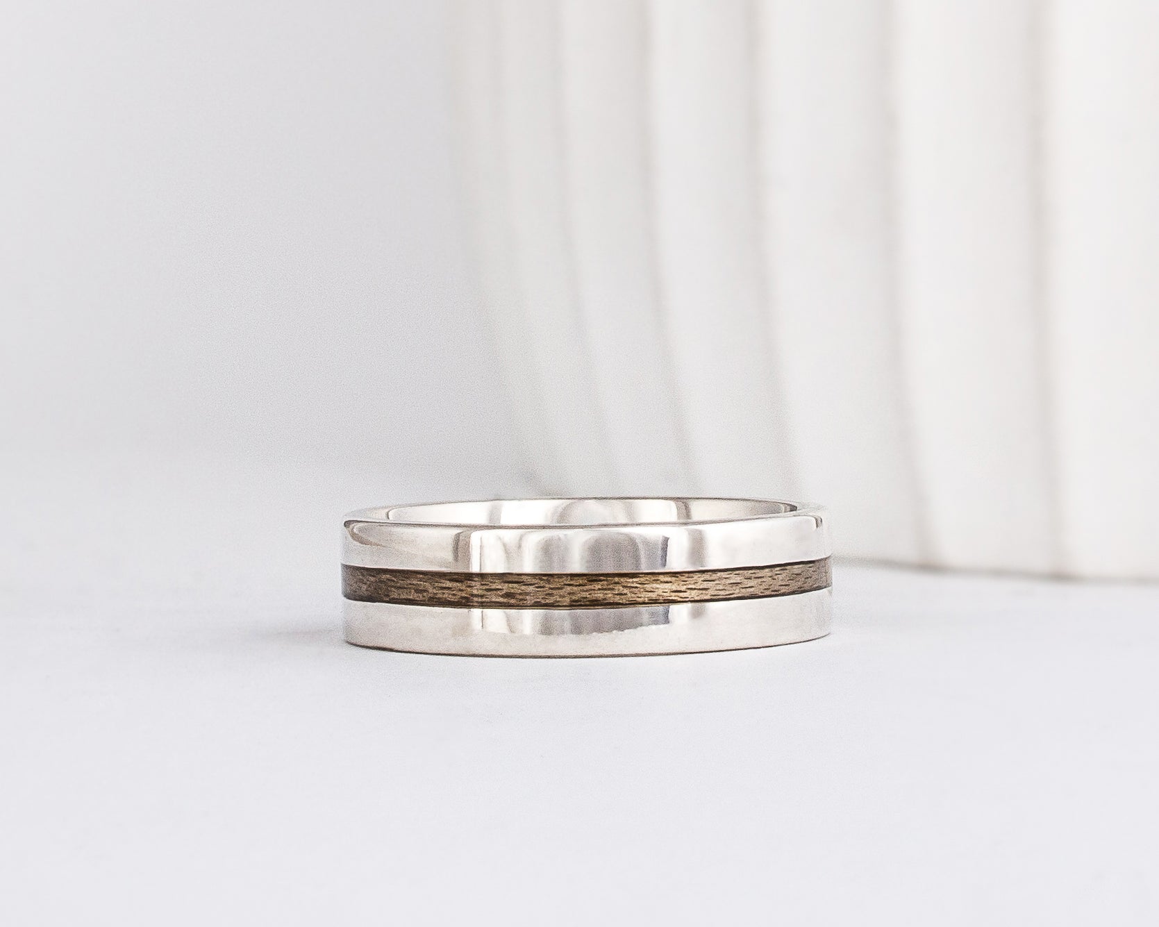 a modern wooden wedding ring for men or women featuring white gold, a flat profile and a central inlay of greyed Maplewood