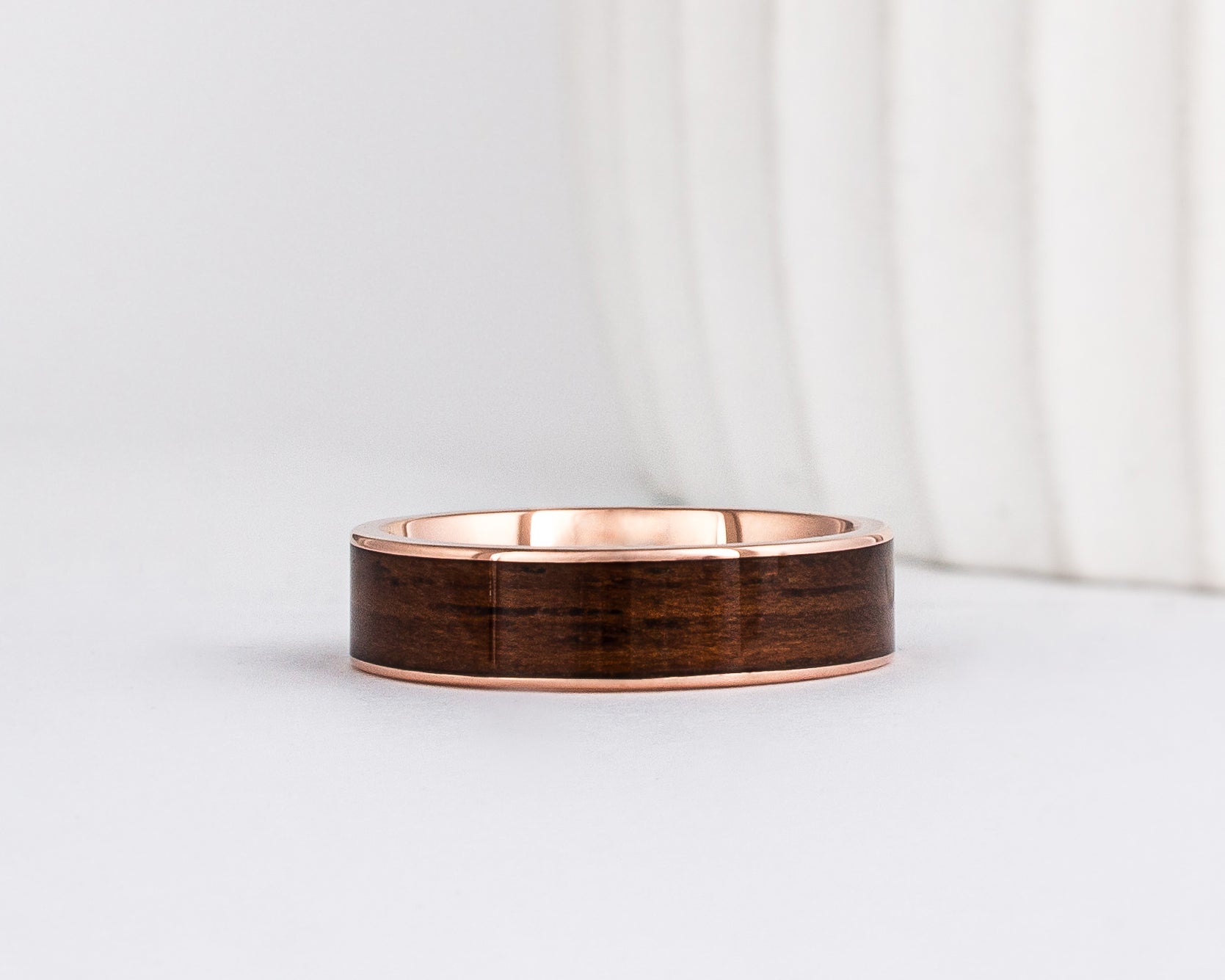 a 6mm gold and wood ring made with rose gold and english oak wood inlay