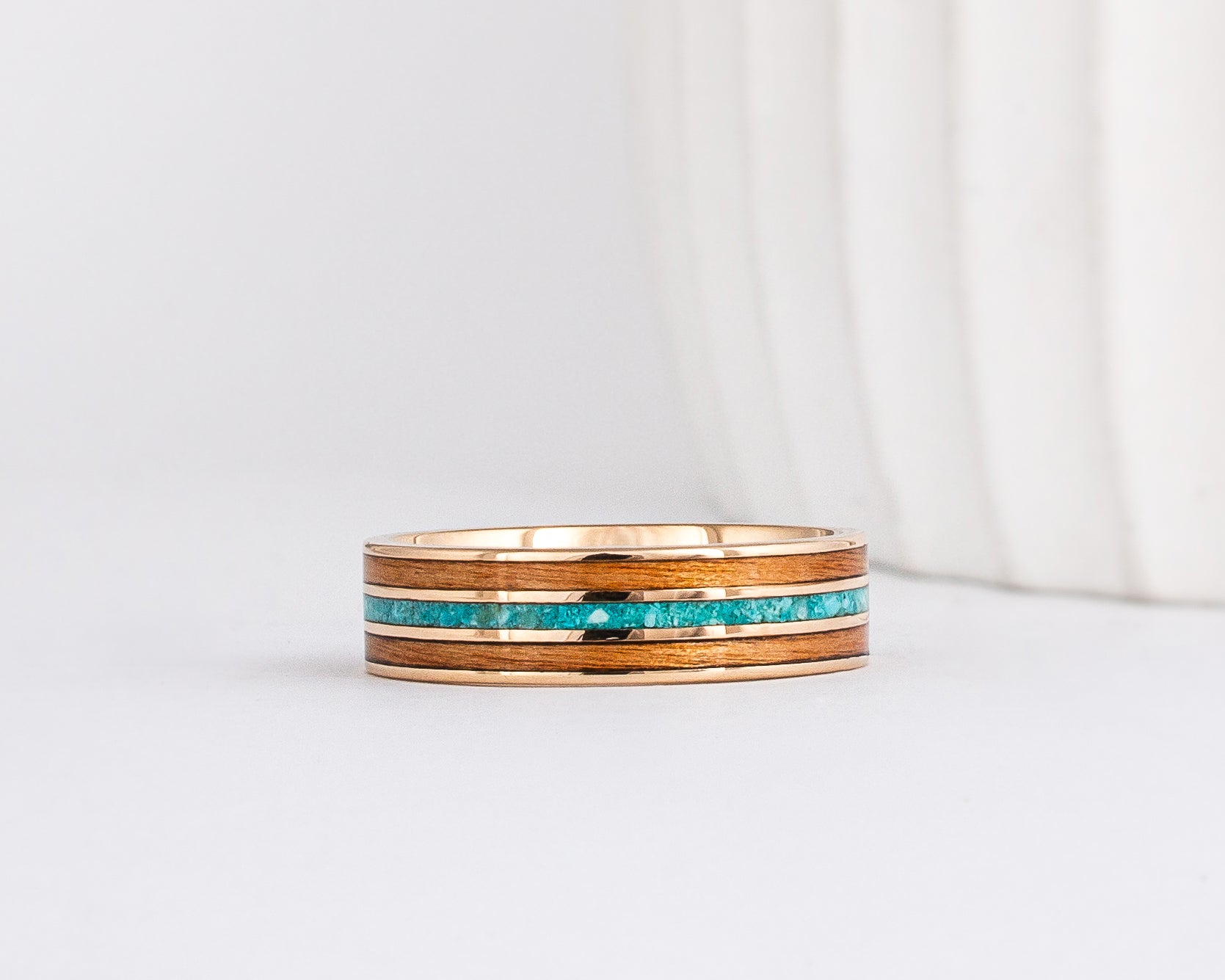 a yellow gold ring with wood inlay made from red alder with a central inlay of sleeping beauty turquoise