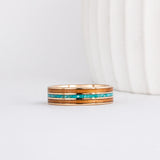 a yellow gold ring with wood inlay made from red alder with a central inlay of sleeping beauty turquoise