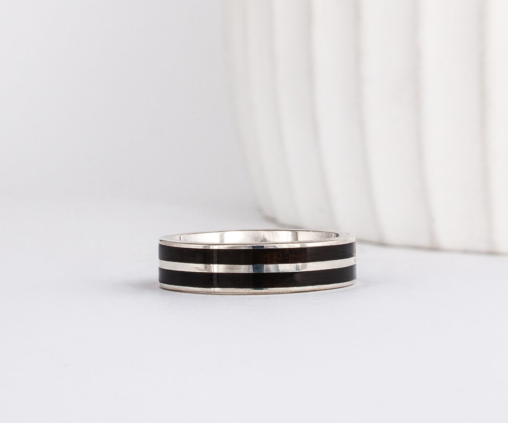 white gold band with straight-styled sleek edge design is inlaid with black ebony wood