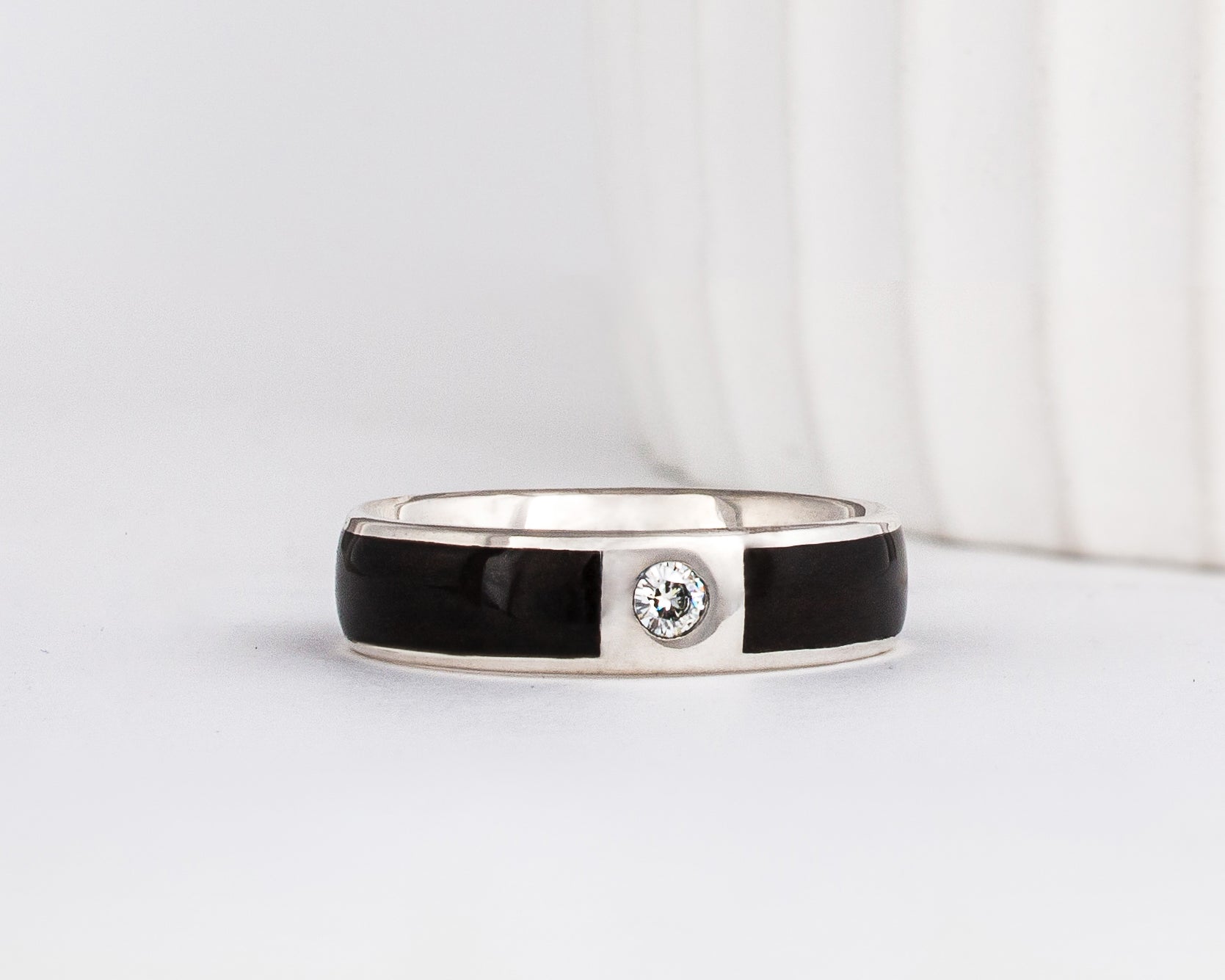 white gold 6mm band with a gypsy set moissanite with dark ebony wood inlays