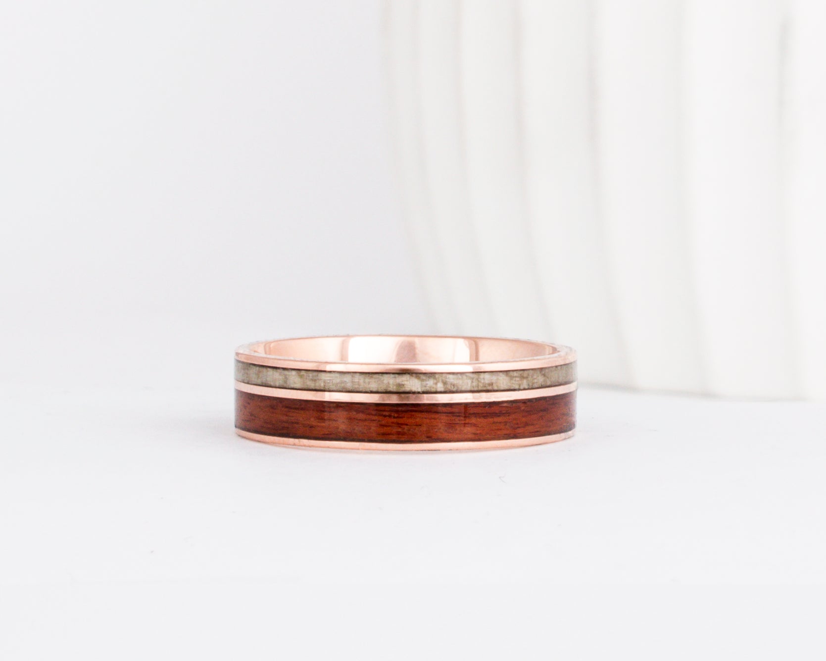 a rose gold wooden wedding ring featuring two wood inlays in complimentary colors.