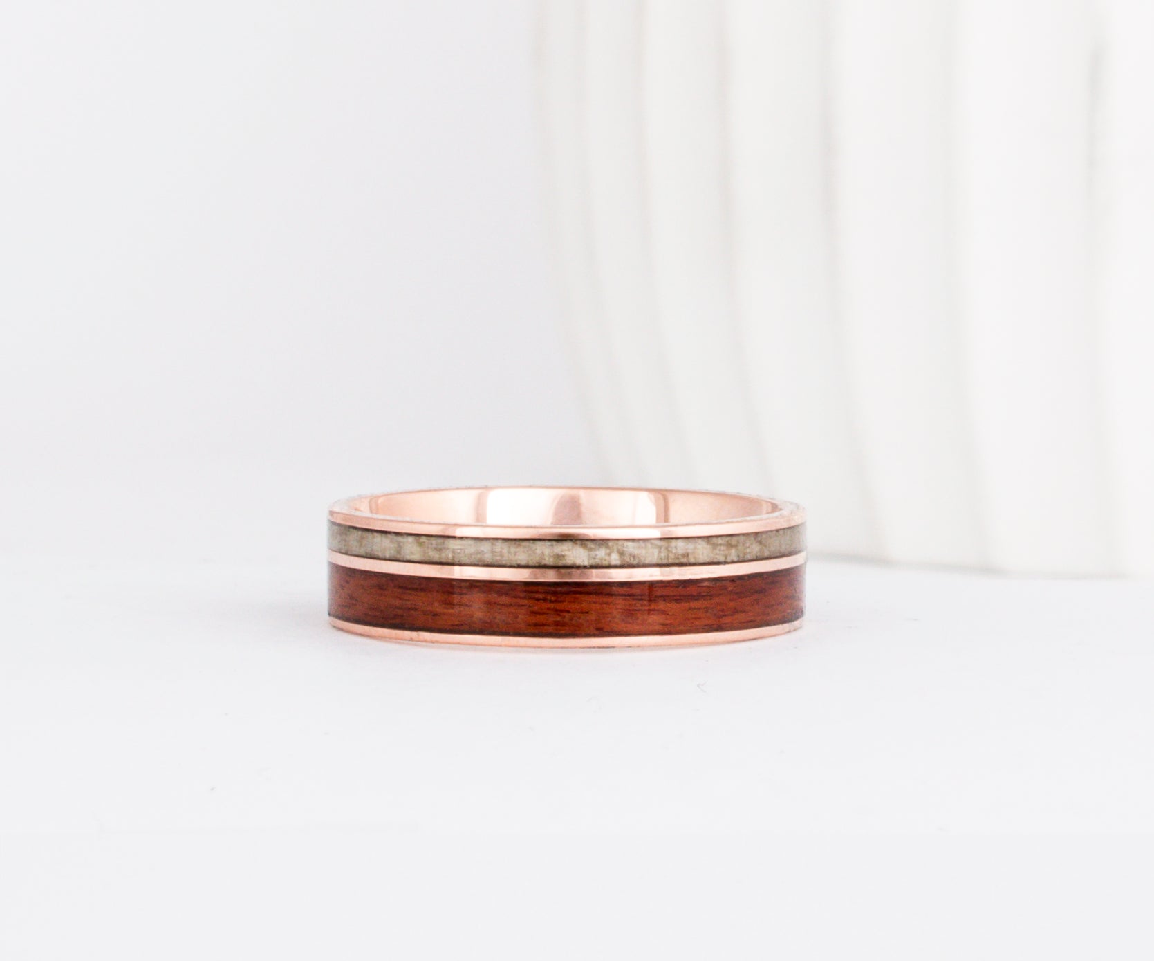 a rose gold wooden wedding ring featuring two wood inlays in complimentary colors.
