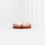 a rose gold wooden wedding ring featuring two wood inlays in complimentary colors.