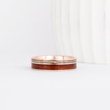 a rose gold wooden wedding ring featuring two wood inlays in complimentary colors.