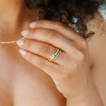 A woman's hand shown wearing the aquamarine bezel set engagement ring along with two delicate ring enhancers to match