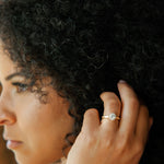 woman touching hair wearing ethically sourced diamond engagement ring featuring moissanite halo