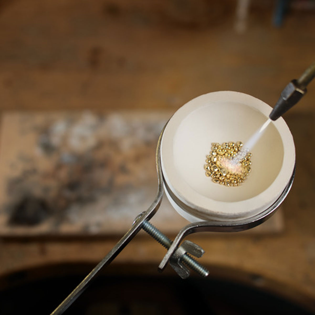 Gold grain is being melted in a crucible by torch. Northwood uses 100% scs certified recycled gold in their custom wood jewelry