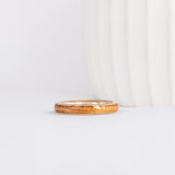 a slim, rounded yellow gold wedding band with a center inlay of american elm wood, giving it a tone on tone look
