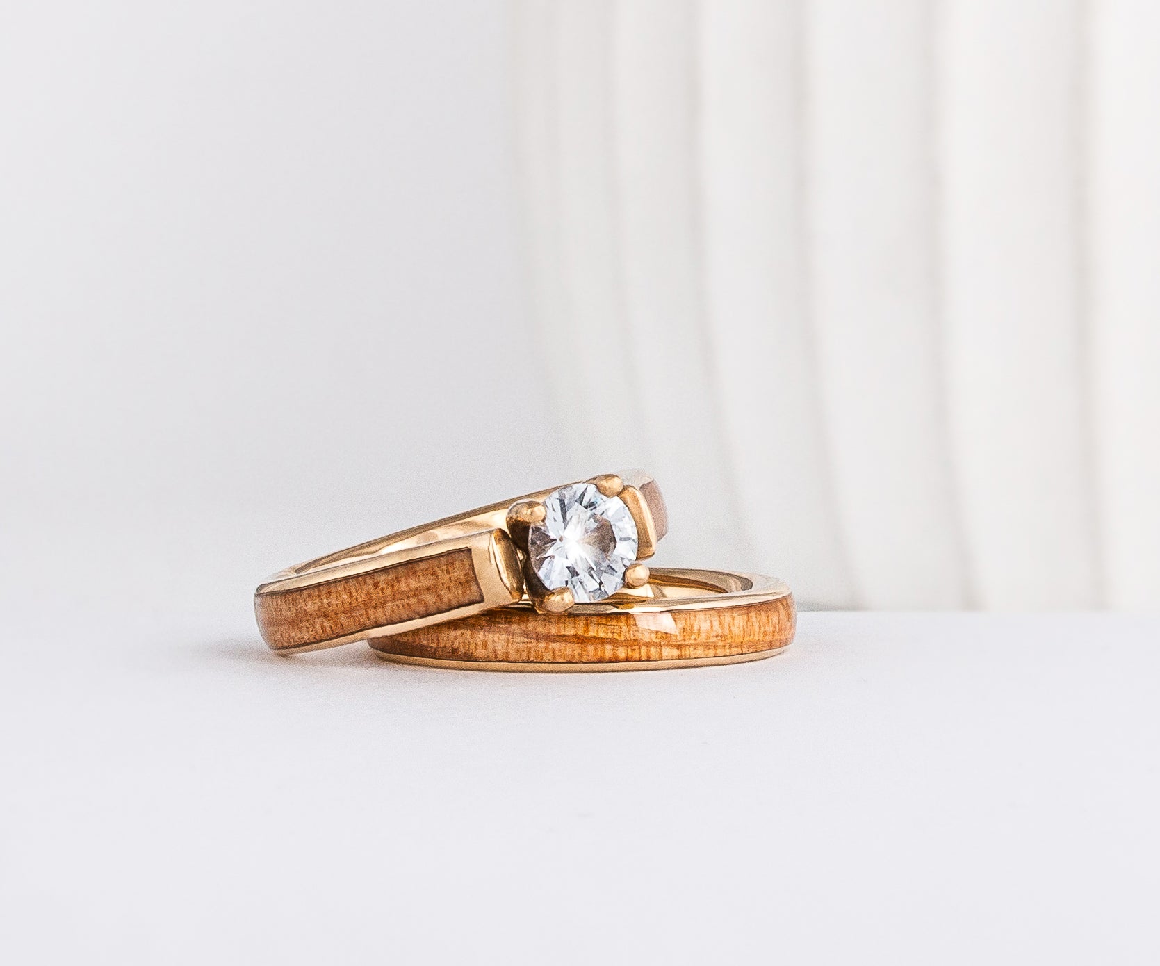 a wood wedding ring set made from yellow gold, american elm wood inlays, and a moissanite solitaire
