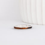 a slim, rounded white gold wedding band with a center inlay of walnut burl wood, giving it a tone on tone look