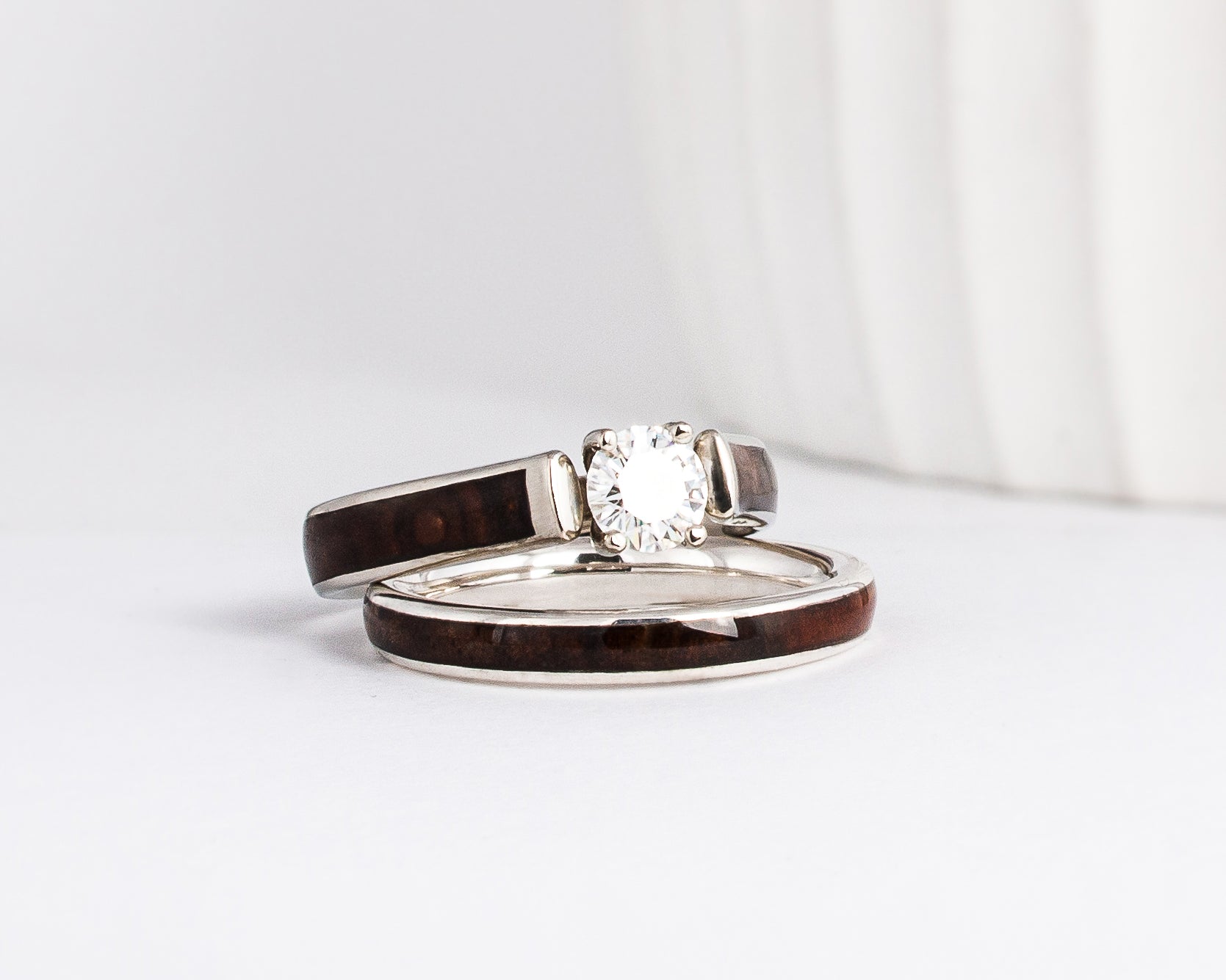 a set of white gold and wood inlay rings is shown with walnut burl wood inlays