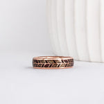 a unique wooden ring, made from rose gold with a delicate laurel leaf floral pattern. Each leaf is filled with wood - alternating between grey maple and purpleheart wood