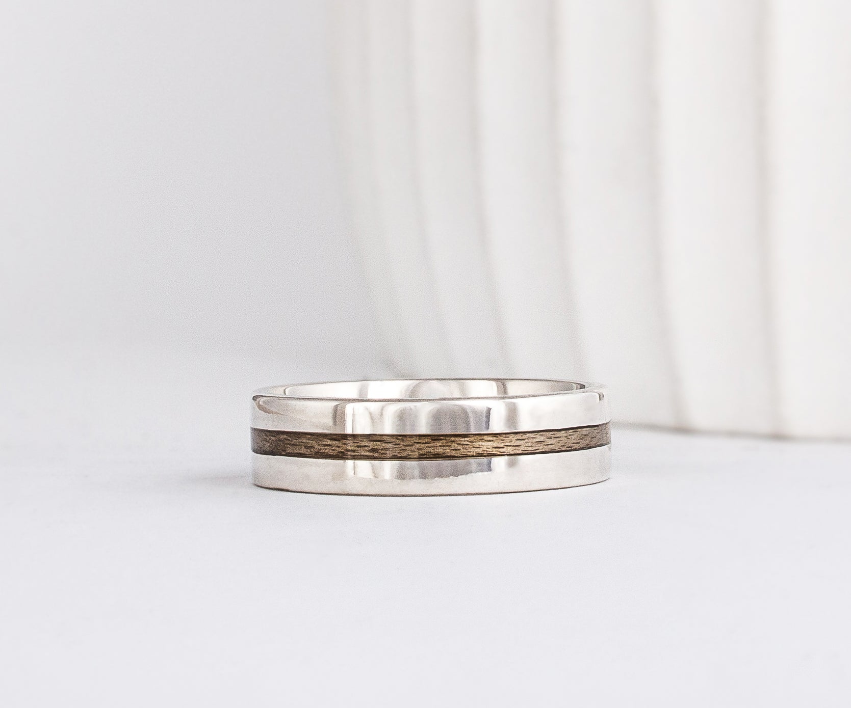 a modern wooden wedding ring for men or women featuring white gold, a flat profile and a central inlay of greyed Maplewood