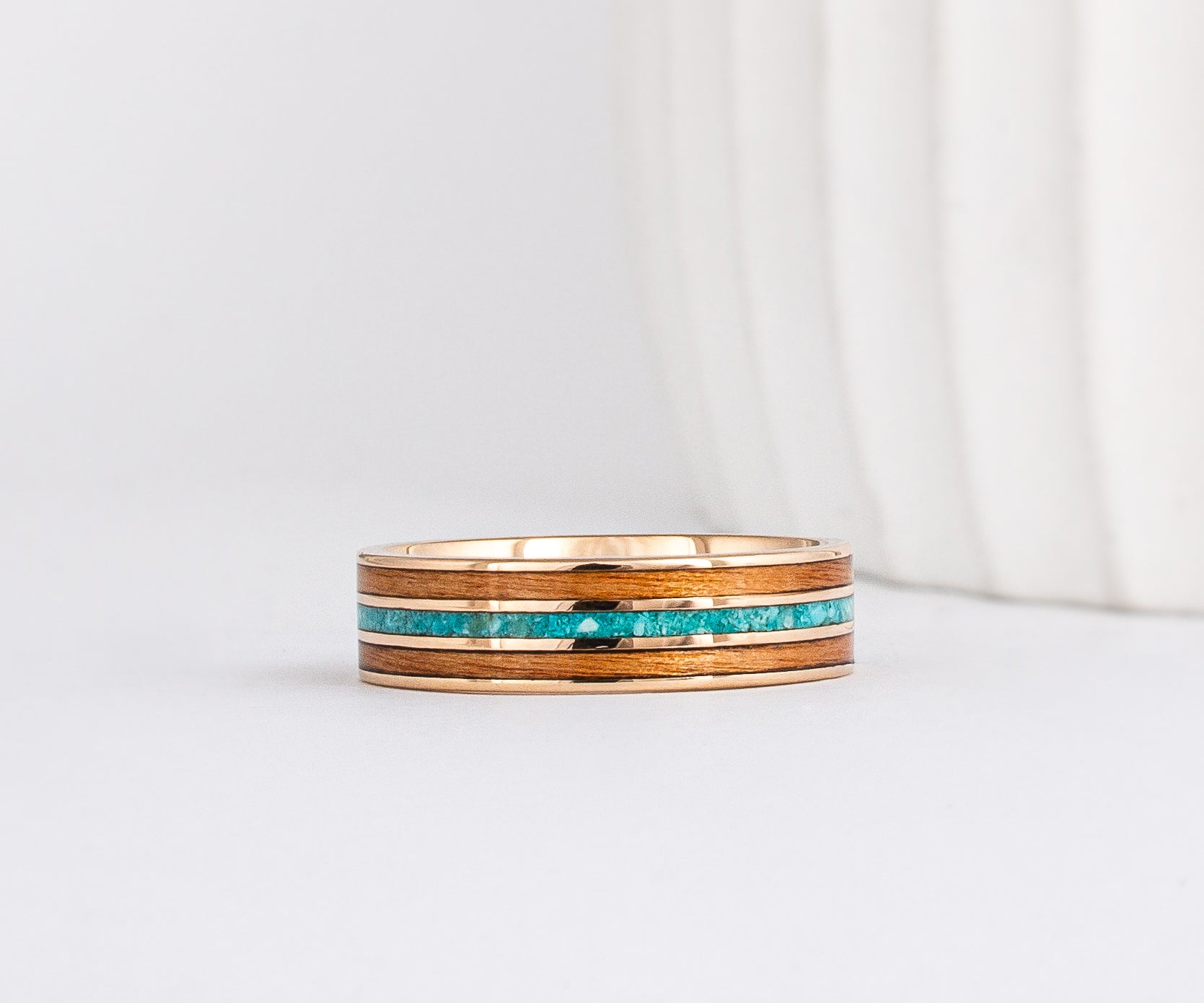 a yellow gold ring with wood inlay made from red alder with a central inlay of sleeping beauty turquoise