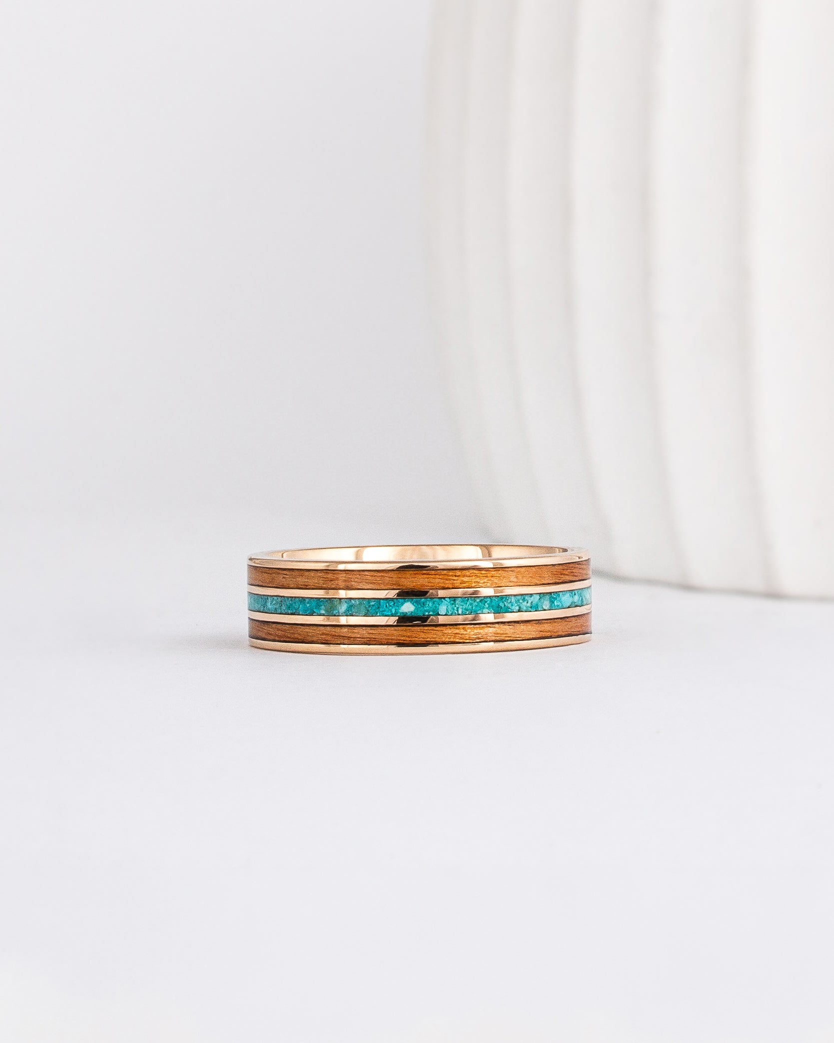 a yellow gold ring with wood inlay made from red alder with a central inlay of sleeping beauty turquoise