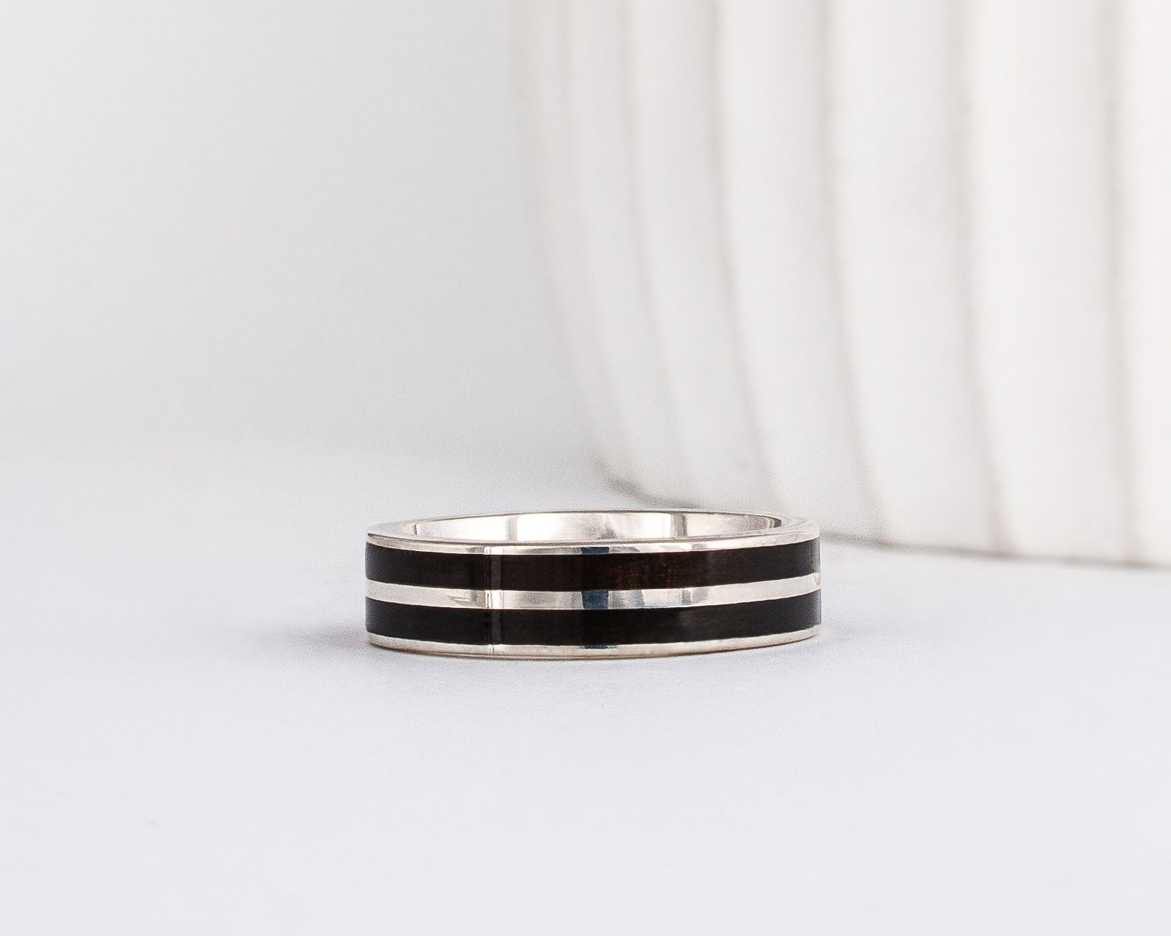 white gold band with straight-styled sleek edge design is inlaid with black ebony wood