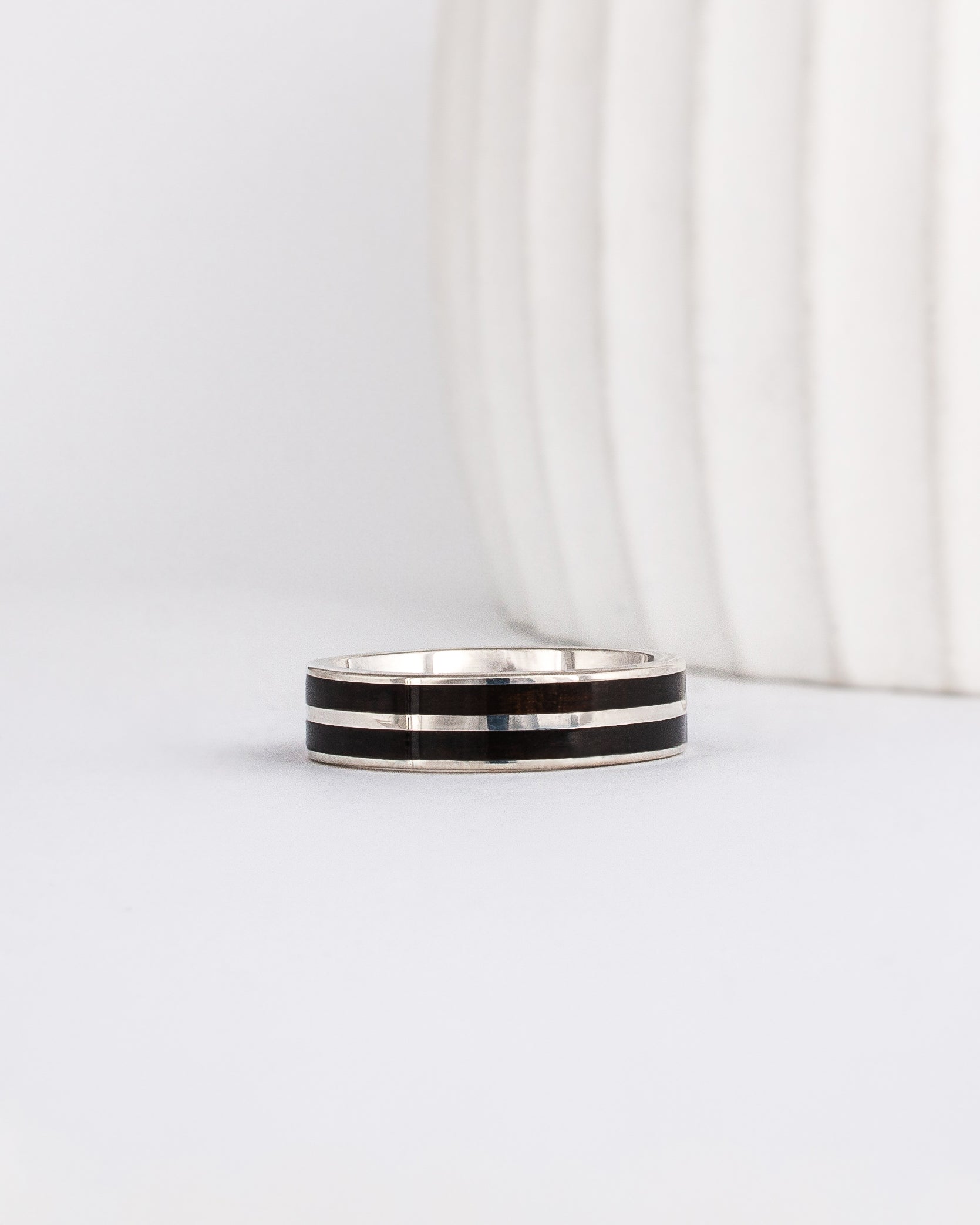 white gold band with straight-styled sleek edge design is inlaid with black ebony wood