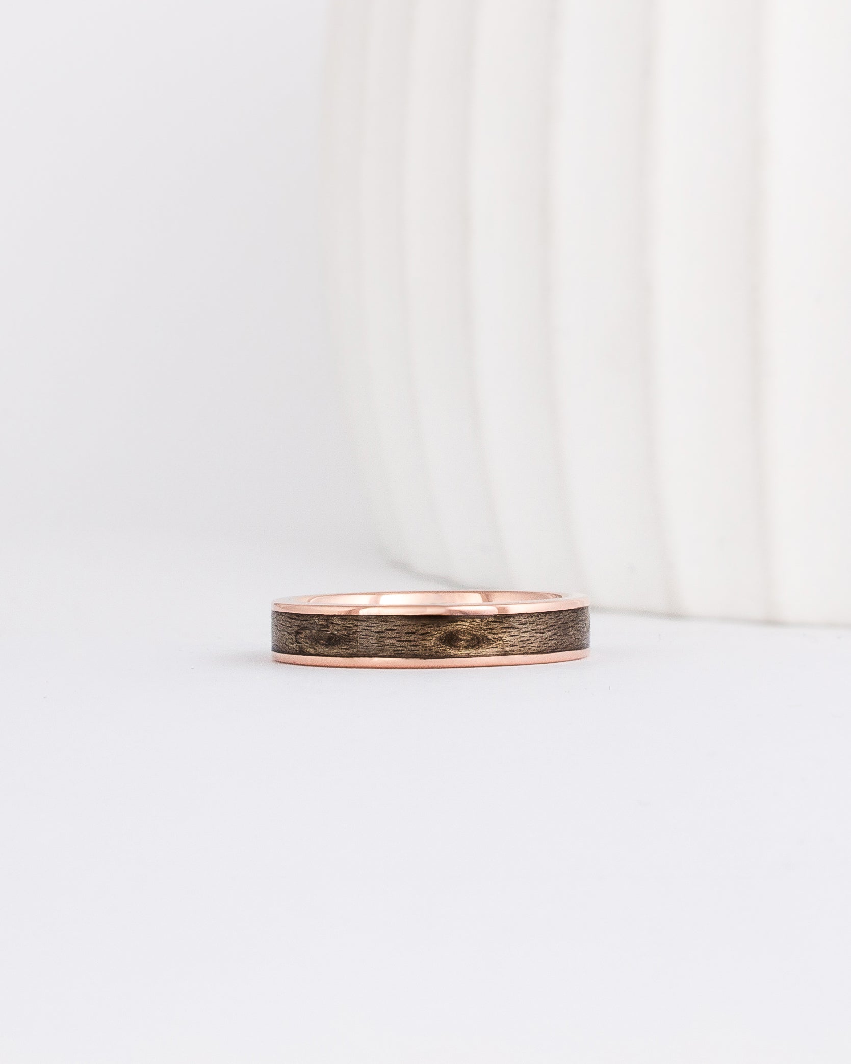 rose gold 4mm band with a straight edge profile with thin gold borders outlining a gray inlay of maple wood