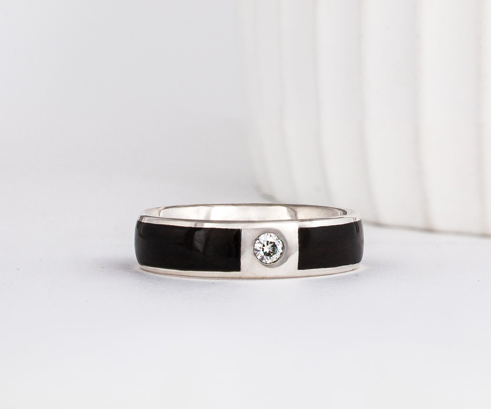 white gold 6mm band with a gypsy set moissanite with dark ebony wood inlays