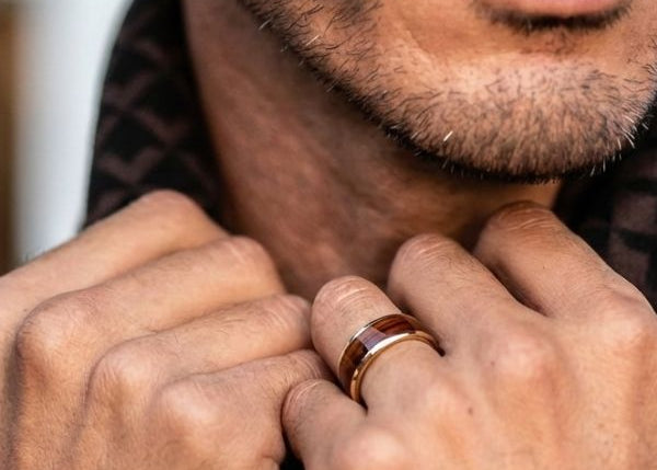 Close-up of a man's hands with a ring, wearing a patterned shirt.