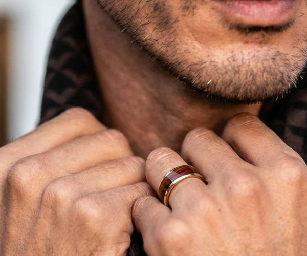 Close-up of a man's hands with a ring, wearing a patterned shirt.
