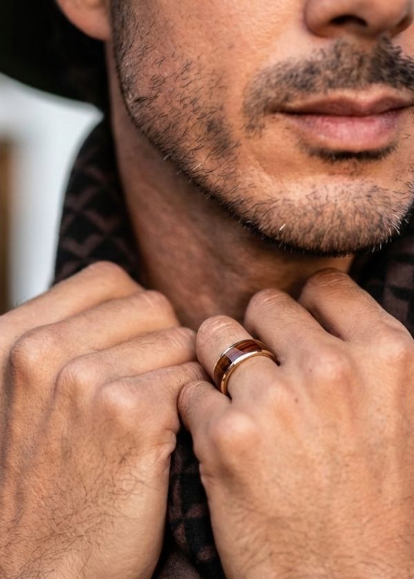 Close-up of a man's hands with a ring, wearing a patterned shirt.