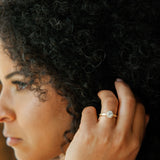 woman touching hair wearing ethically sourced diamond engagement ring featuring moissanite halo