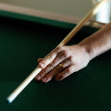 a man holds a pool cue while wearing a square profile wedding ring in yellow gold